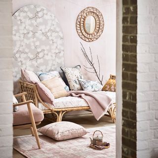 A pale pink living room with blossom wallpaper panel behind chaise