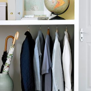 shirts hung up in a wardrobe with globe and files above
