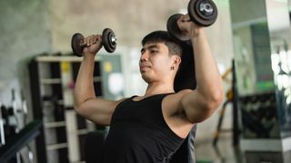 A man performing seated dumbbell shoulder press at the gym