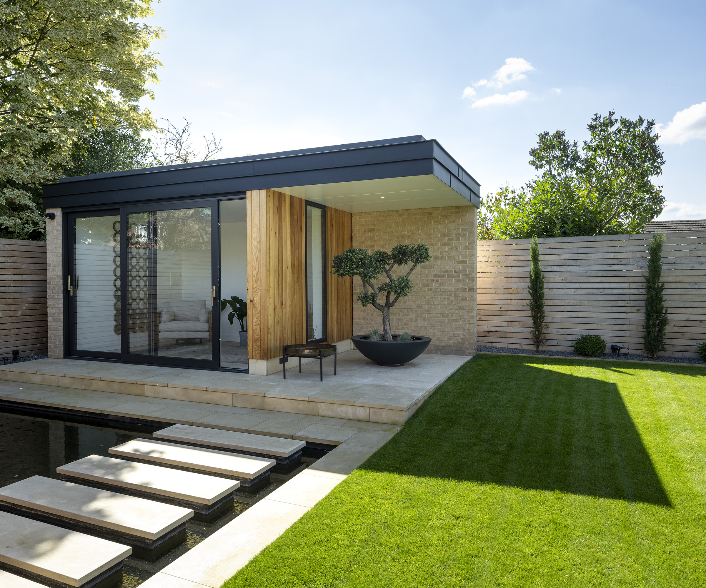 A garden room in a newly landscaped garden with lawn and fence