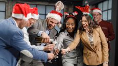 Smiling businessman pours champagne for his colleagues during a Christmas party in the office