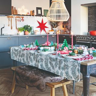 A dining table in the kitchen set for a Christmas dinner with a botanical-print tablecloth