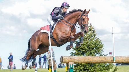 Sarah Bullimore rides a chestnut horse over a cross-country corner