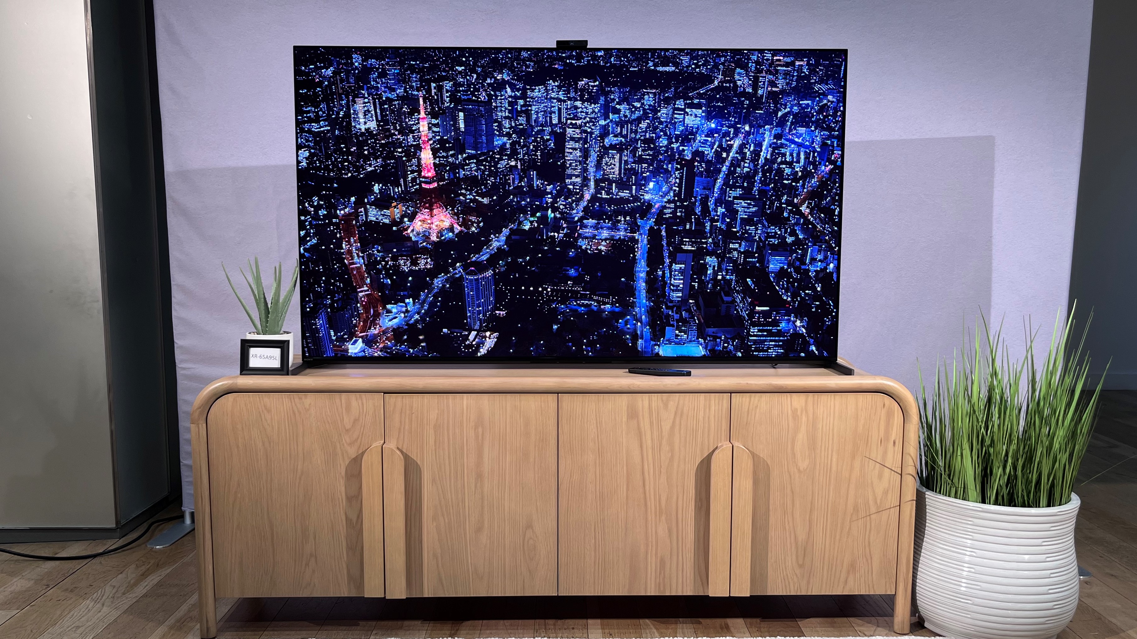 TV Sony A95L QD-OLED sur un support TV montrant une image de ville à l'écran
