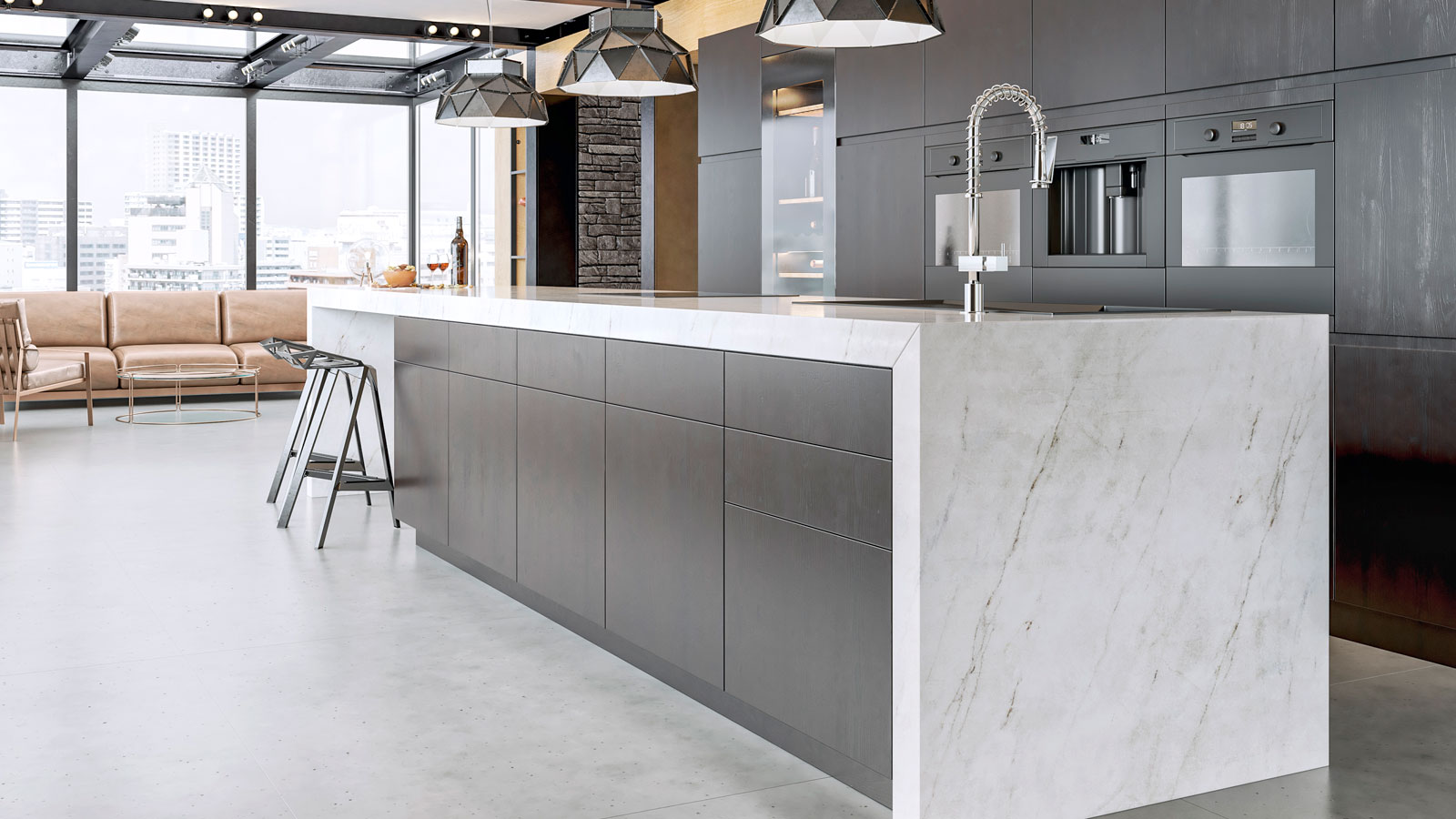 Contemporary apartment with large marble worktop and island with a bank of dark kitchen units in backgound.