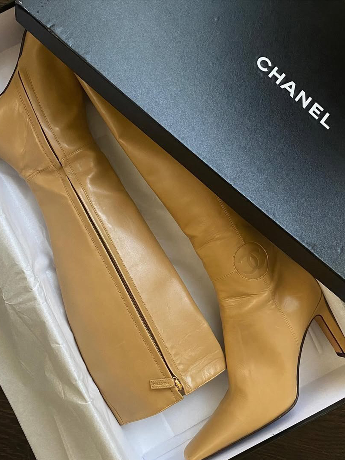 A pair of vintage Chanel tan boots in the box.