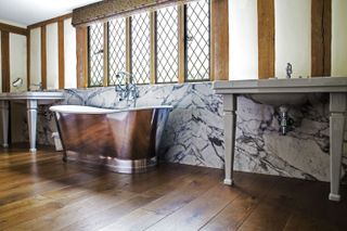 freestanding bath in period bathroom with traditional solid wood flooring