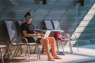 A person doing work on a computer by a pool