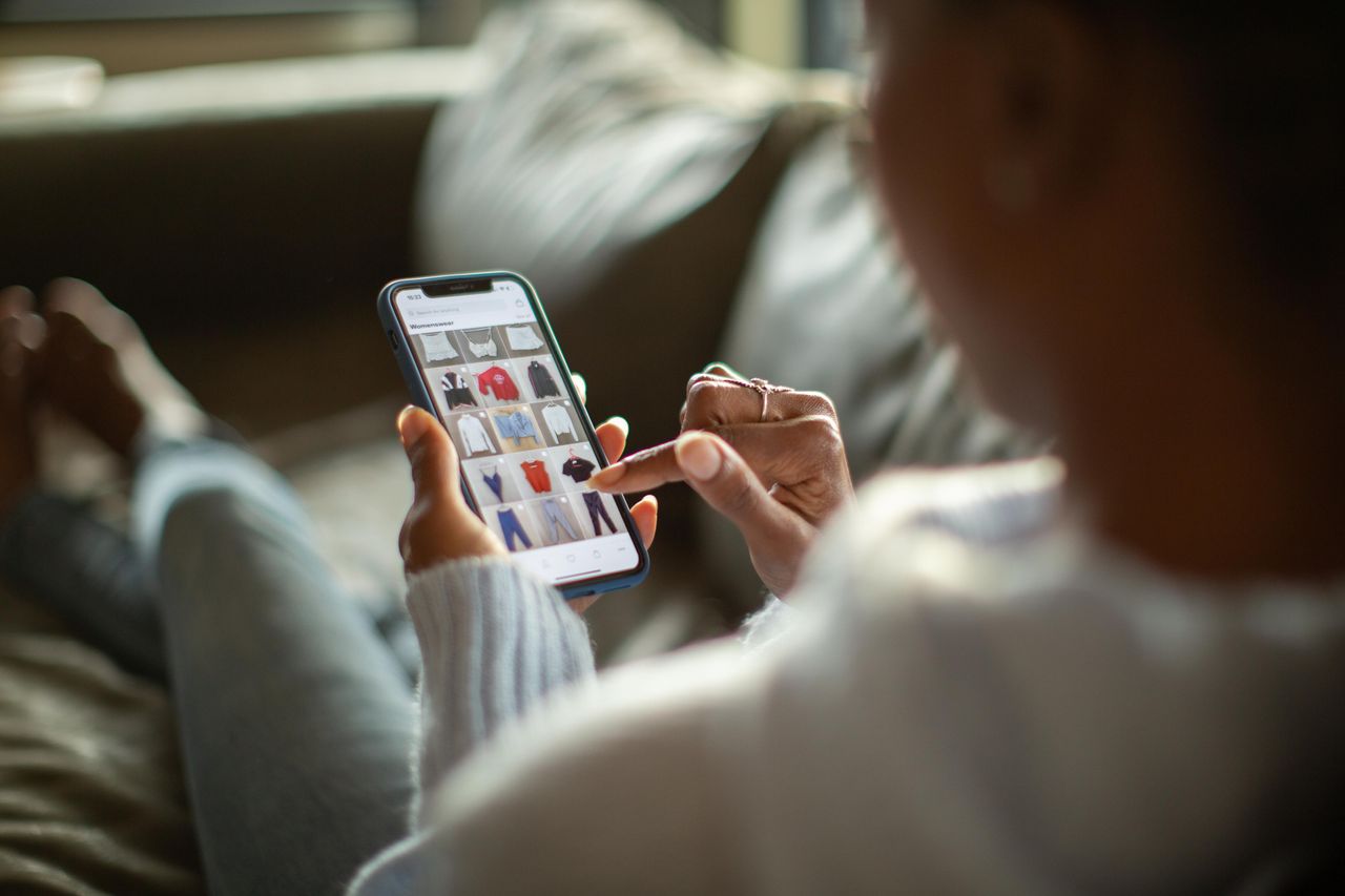 A woman sitting on a sofa with her feet up scrolling sales on Cyber Monday 
