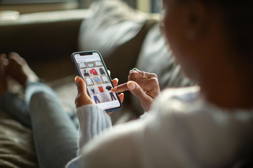 A woman sitting on a sofa with her feet up scrolling sales on Cyber Monday 