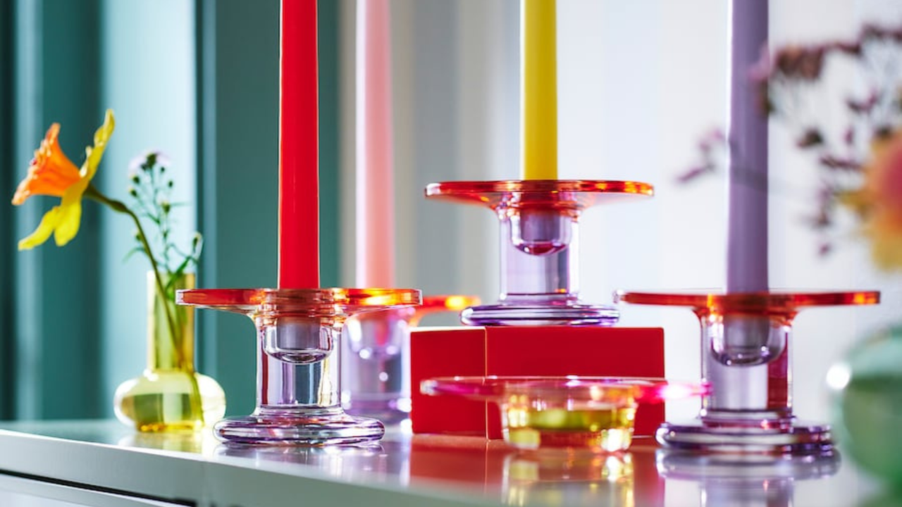 Four JARLIK candlestick holders and a yeallow JARLIK vase holding a daffodil.