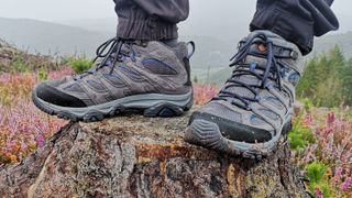 Person's feet standing on rock wearing Merrell Moab 3 Mid GTX hiking boots