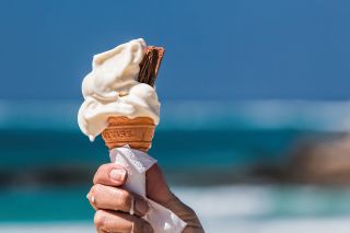 An ice cream cone with ice cream melting in the sun.