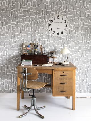 vintage desk with gray graphic Miss Print wallpaper, white floor, craft/sewing accessorises and lamp on desk, vintage chair