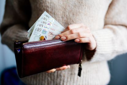 Woman taking £10 notes out of her wallet