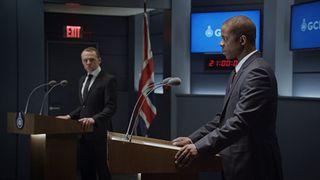 Simon Pegg and Adrian Lester stand at podiums in The Undeclared War