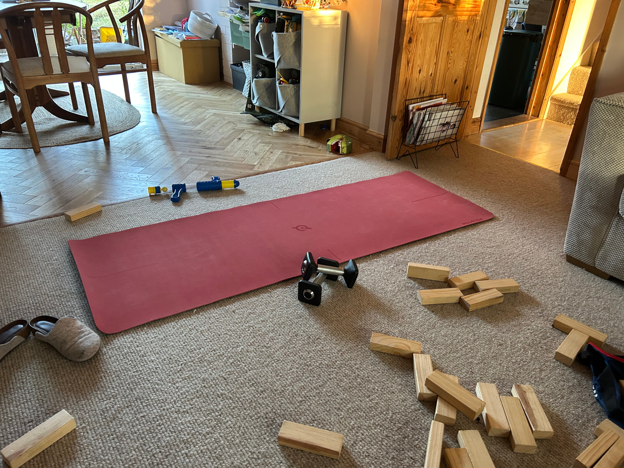 Exercise mat and dumbbells in a domestic setting, surrounded by kids toys