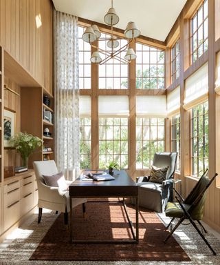 marie flanigan designed sun room with large tall ceilings windows and a large central desk with multiple chairs