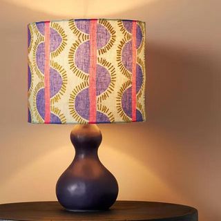 A table lamp with a red and blue patterned shade