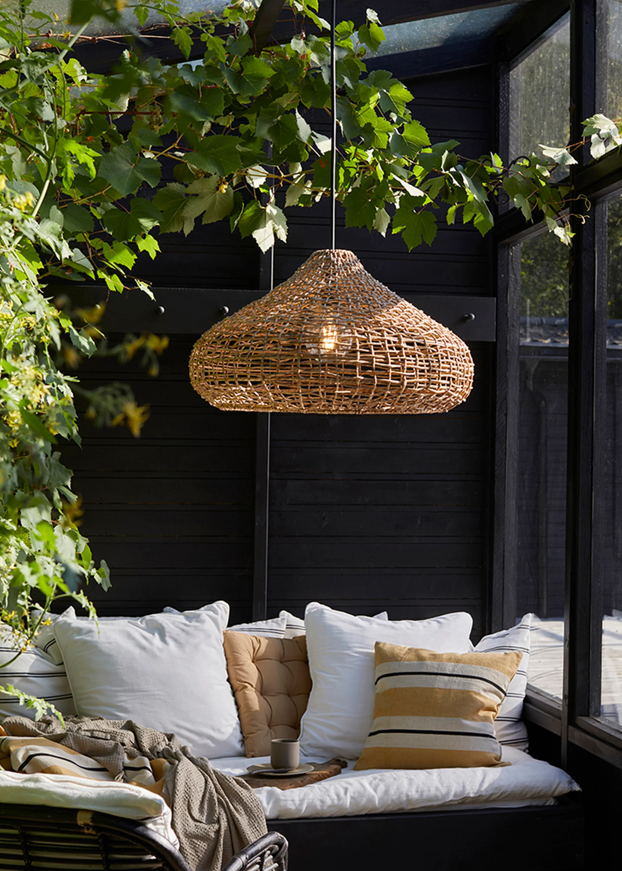 rattan pendant light over an outdoor sofa with scatter pillows