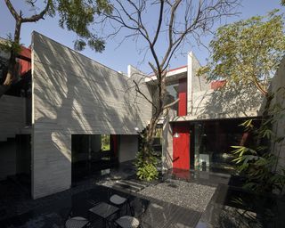 concrete volumes and green courtyard at Trees Sliced Through by Matharoo Associates