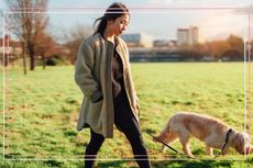 A woman walking her dog in a field