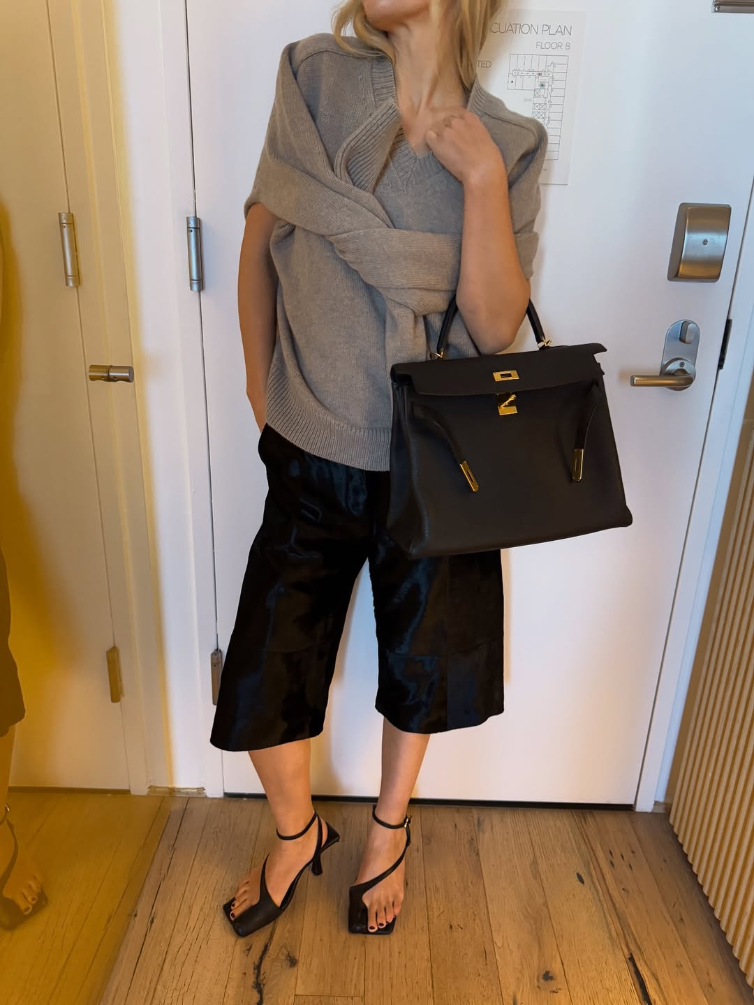 Influencer Stephanie Broek wearing culottes with a knitted vest and strappy heels.