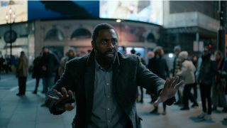 Idris Elba stands in Piccadilly Circus with a panicked look in Luther: The Fallen Sun.