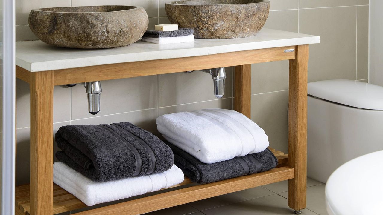 bathroom with open shelving vanity with pile of towels