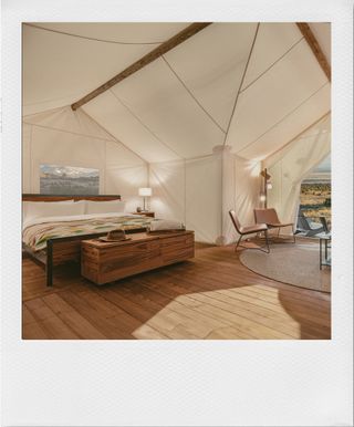 A white tented hotel room with a bed and chairs