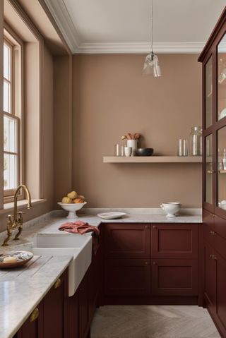 warming terracotta colored kitchen with brown cabinetry, marble countertops, open shelf, custom cabinetry, brass vintage tap
