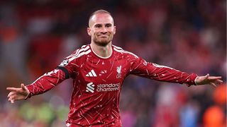 Alexis Mac Allister, wearing the red of Liverpool, holds his arms out stretched in celebration at scoring in the Champions League 2026/27
