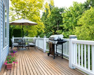 Clean outdoor cedar wooden deck and patio of home with BBQ cooker and bottled beer