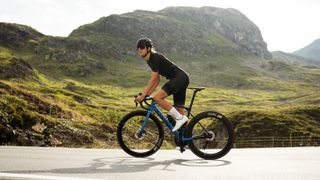 A women riding the Canyon Ultimate CF SL 7 with mountains in the background