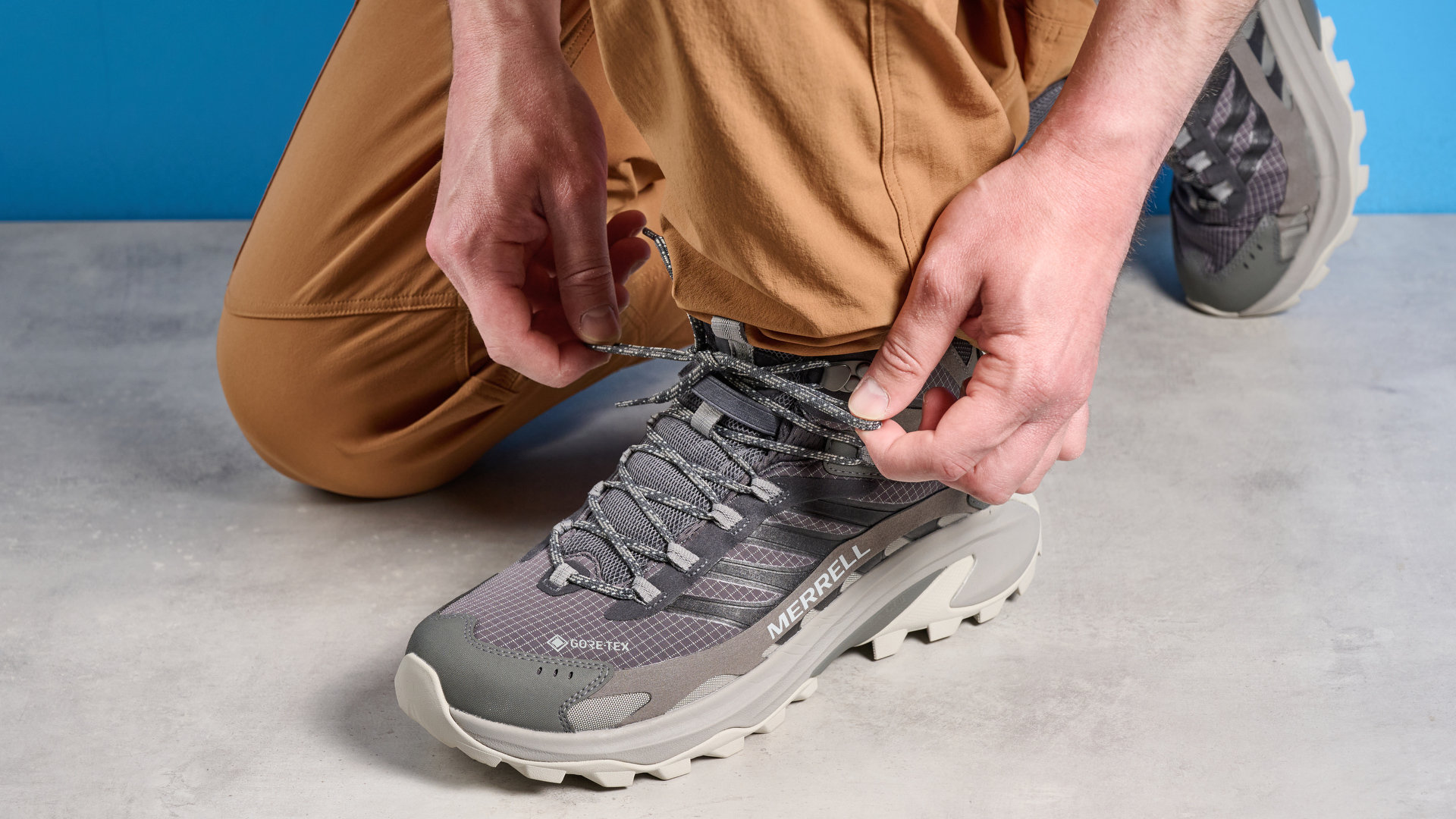 A photo of the Merrell Moab Speed 2 boots against a blue background