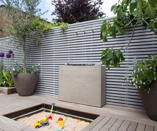 children's sandpit hidden in a raised backyard deck