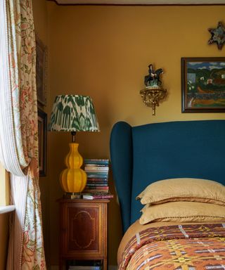 yellow bedroom with blue headboard and eclectic decor
