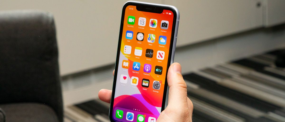 An iPhone 11 in someone&#039;s hand, with the screen on