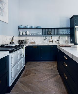 Kitchen area with a light blue aga, white marbled worktops and fitted cabinets, dark wood flooring