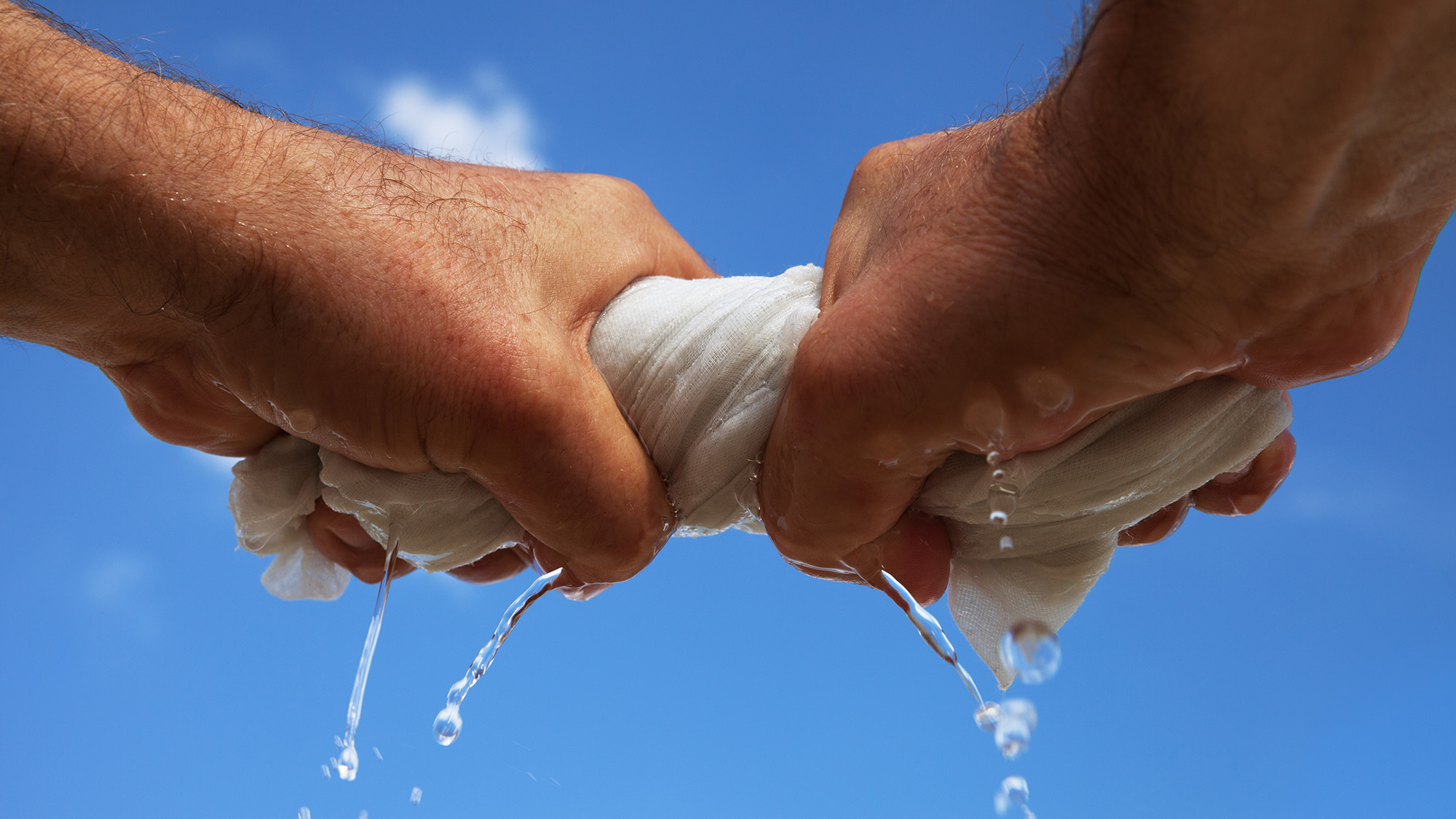 Man wringing out wet white towel outside