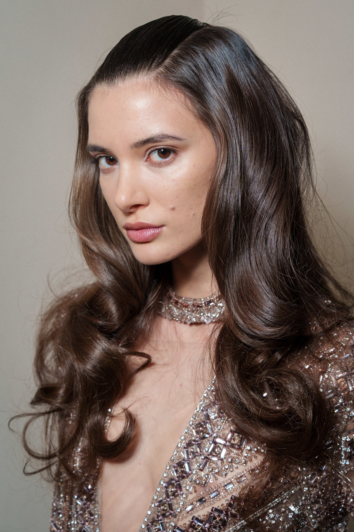 A model showing off a pulled back wedding hairstyle and a sparkly gown