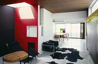 The living space with red wall and furniture pieces