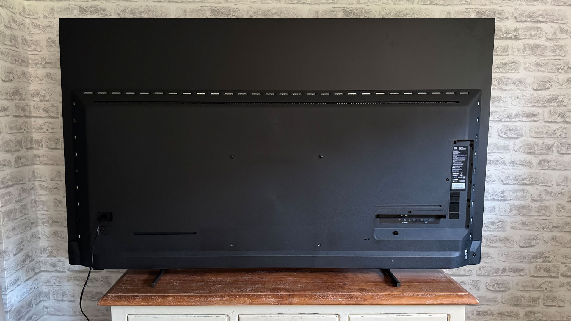 Philips OLED760 OLED TV in front of brick wall, rear of set
