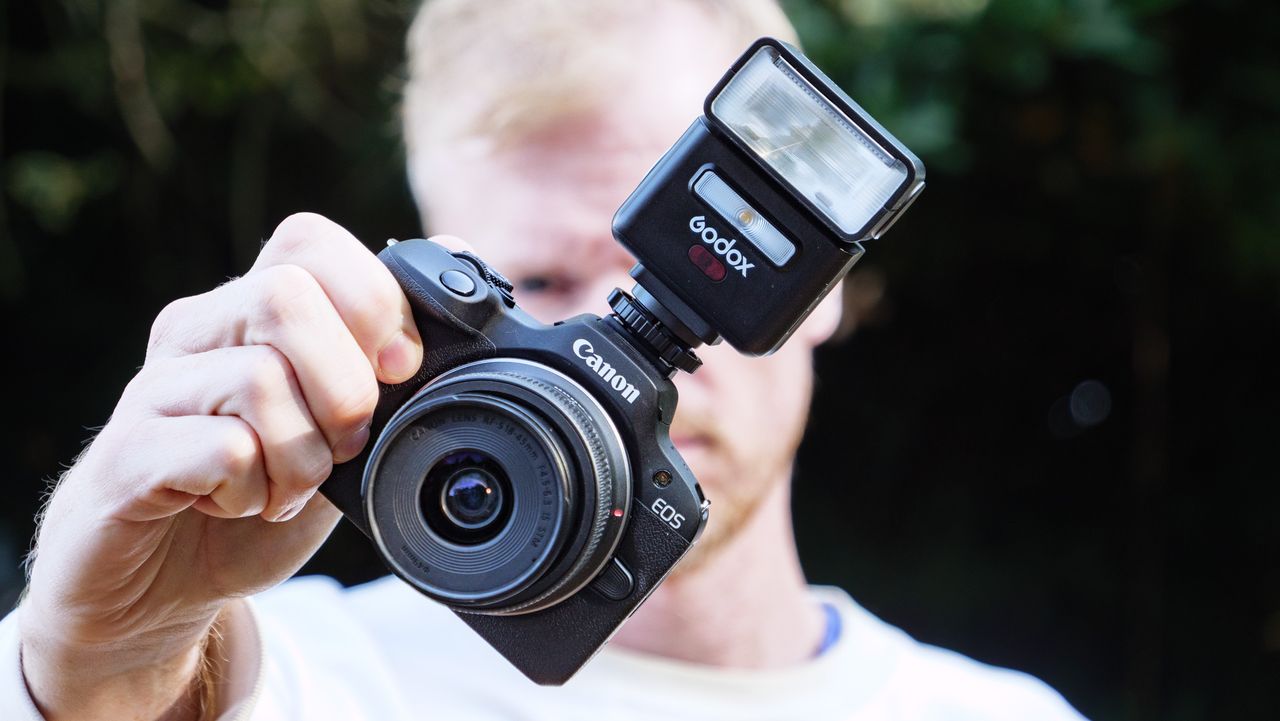 Godox iT32 camera flash attached to a Canon camera, held by photographer and TechRadar's Cameras Editor Tim Coleman
