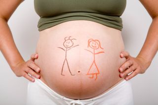 A woman's pregnant belly has a girl and boy drawn on it to illustrate the ramzi theory