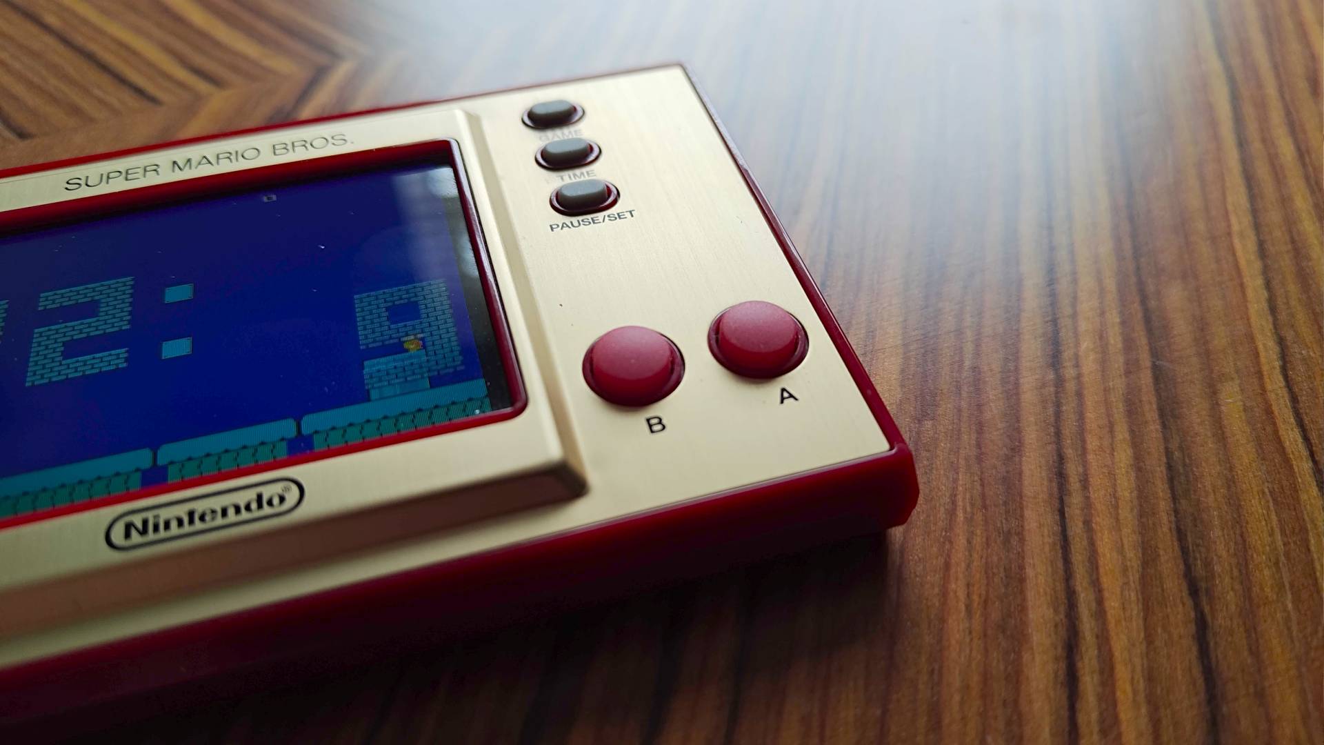 Close up of Mario Game and Watch rubber buttons sitting on woodgrain desk.