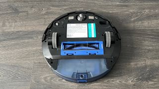 Eufy RoboVac G30 Hybrid upside down on a wooden floor without the mopping pad attached