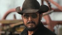 Close-up of Rip in black cowboy hat and sunglasses standing outside on ranch in Dutton Ranch