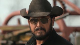Close-up of Rip in black cowboy hat and sunglasses standing outside on ranch in Dutton Ranch