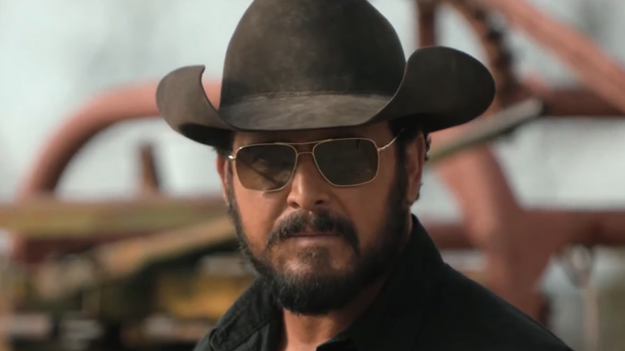 Close-up of Rip in black cowboy hat and sunglasses standing outside on ranch in Dutton Ranch